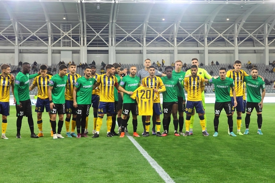 Πριν τη σέντρα οι ποδοσφαιριστές των δύο ομάδων φωτογραφήθηκαν κρατώντας φανέλα στα χρώματα της ΑΕΛ με το όνομα του Χρυσοβαλάντη Καπαρτή